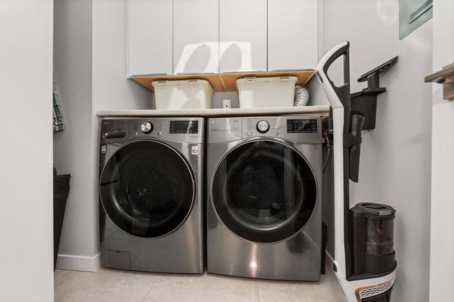 Washroom featuring light tile patterned flooring, cabinet space, baseboards, and washer and dryer | Image 30