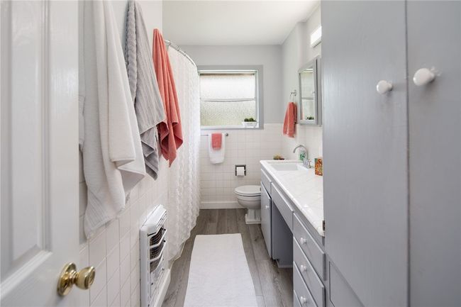 Bathroom featuring heating unit, tile walls, wood finished floors, vanity, and toilet | Image 15