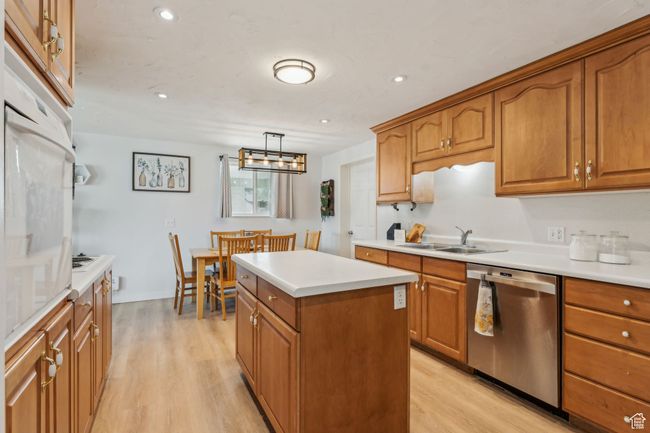 Kitchen with brown cabinetry, dishwasher, a sink, and light wood-style floors | Image 7