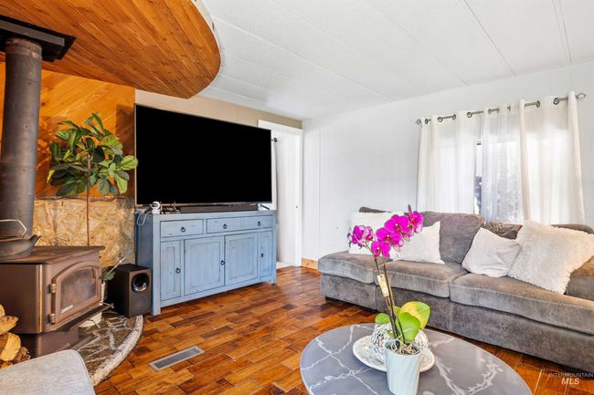 Living room with a wood stove, wood finished floors, and wood walls | Image 5