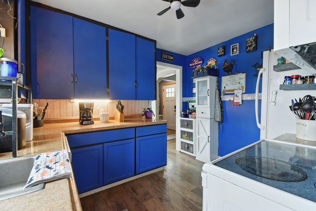 Kitchen featuring white electric range, a ceiling fan, blue cabinetry, dark wood-type flooring, and light countertops | Image 19