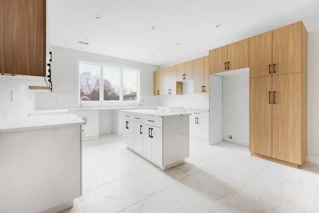 Kitchen with decorative backsplash, a center island, white cabinets, and sink | Image 24
