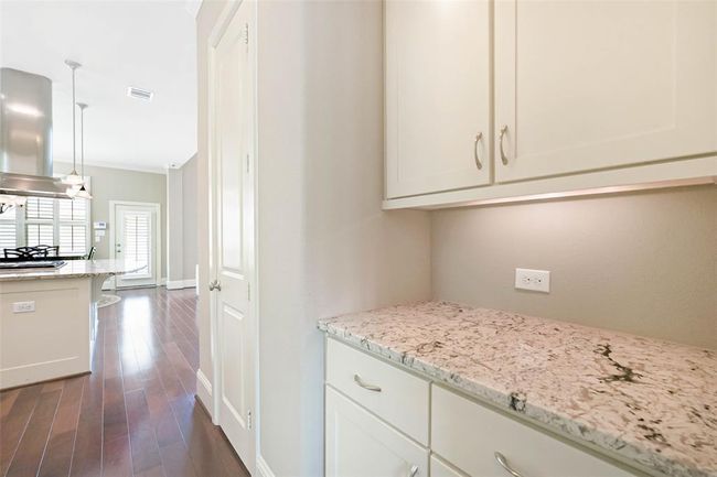 Convenient butler’s pantry or coffee station with granite countertops, upper and lower cabinetry, and under-cabinet lighting—perfect for extra storage and serving space just off the kitchen. | Image 22