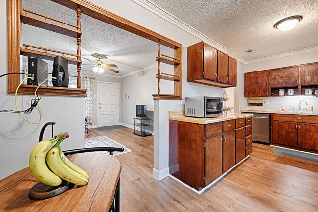 Dining area and kitchen view with stainless steel appliances, vintage open shelves, light countertops, and new LVP flooring. | Image 7