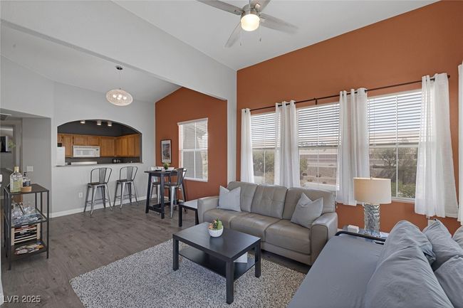 Living area featuring a ceiling fan, baseboards, a healthy amount of sunlight, wood finished floors, and lofted ceiling | Image 14