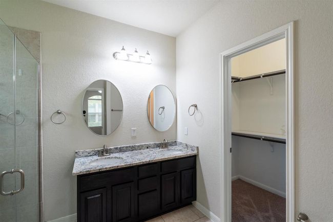 Primary bathroom with granite countertops, dual vanity, and walk-in closet. | Image 25