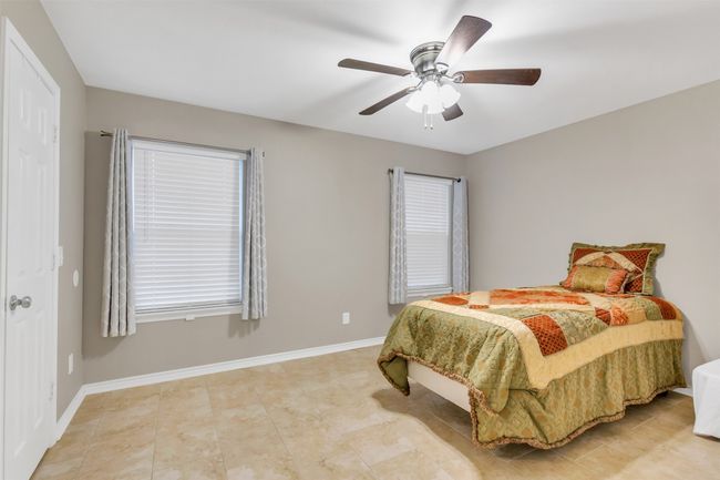 Bedroom featuring a ceiling fan, multiple windows, and light tile patterned floors | Image 9