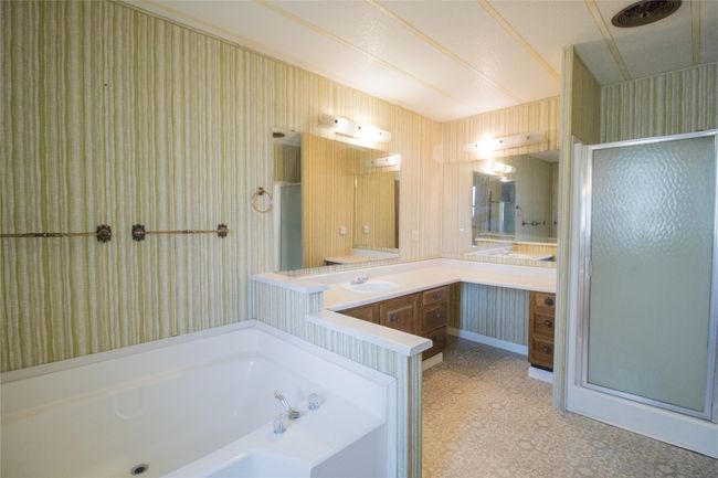 Full bath featuring a shower stall, vanity, a bath, and tile patterned floors | Image 11