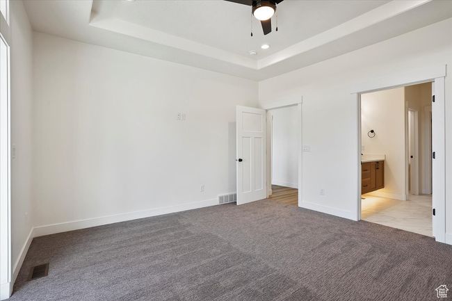 Unfurnished bedroom with baseboards, light carpet, visible vents, and a raised ceiling | Image 9