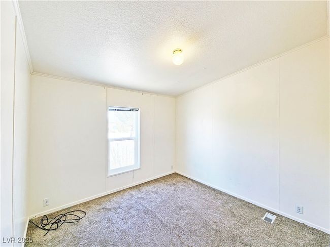 Spare room with a textured ceiling, crown molding, carpet flooring, visible vents, and baseboards | Image 20