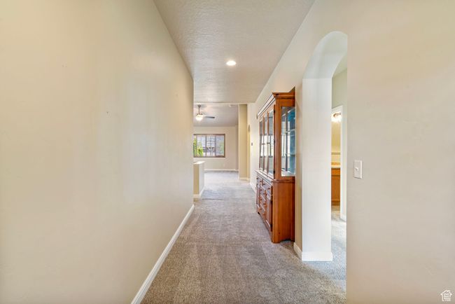 Corridor with light carpet, baseboards, arched walkways, and a textured ceiling | Image 17