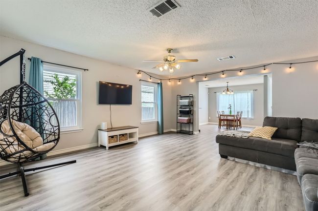 Living area with a textured ceiling, rail lighting, healthy amount of natural light, and light wood finished floors | Image 5