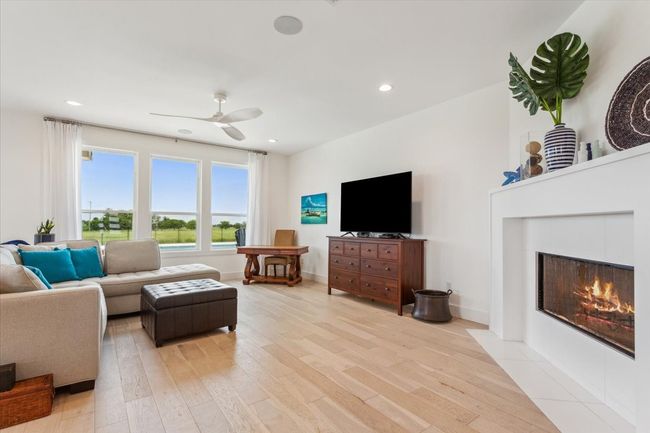 Living area with light wood-type flooring, a ceiling fan, a tile fireplace, recessed lighting, and baseboards | Image 11