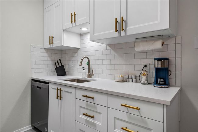 Kitchen featuring stainless steel dishwasher, decorative backsplash, and white cabinetry | Image 14