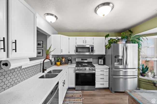 Kitchen featuring stainless steel appliances, white cabinetry, backsplash, and dark wood finished floors | Image 10