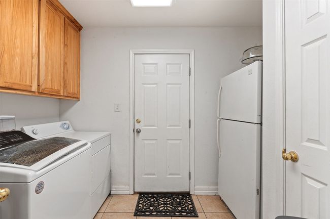 Washroom with independent washer and dryer, light tile patterned floors, cabinet space, and baseboards | Image 33