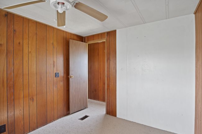 Carpeted empty room with ceiling fan and wood walls | Image 14