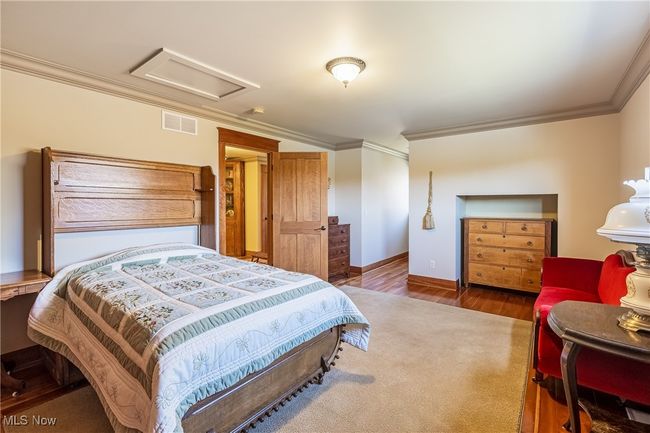 Bedroom featuring wood finished floors, visible vents, baseboards, attic access, and crown molding | Image 38