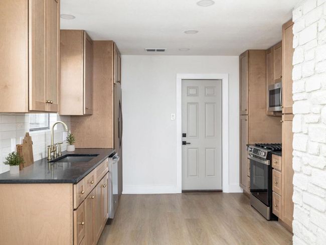 Kitchen featuring visible vents, a sink, dark countertops, backsplash, and appliances with stainless steel finishes | Image 15