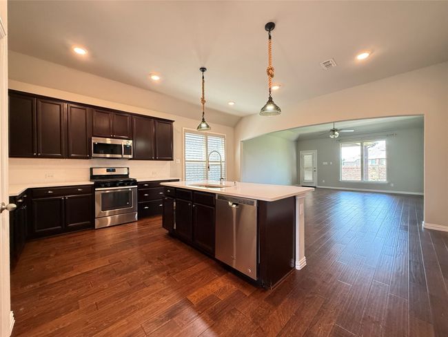 Kitchen featuring appliances with stainless steel finishes, a sink, plenty of natural light, a ceiling fan, and lofted ceiling | Image 7
