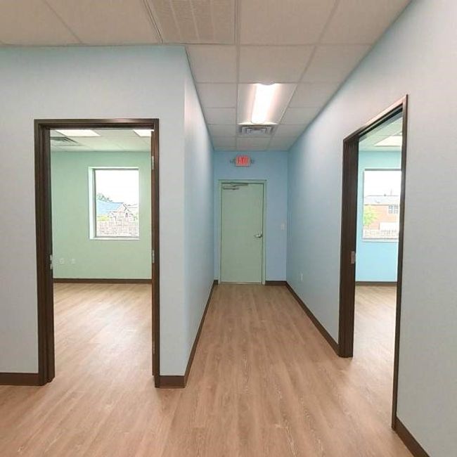 Corridor with a drop ceiling, light wood-style flooring, baseboards, and healthy amount of natural light | Image 4