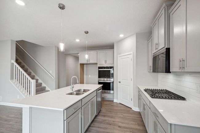 Thoughtfully-designed, modern & fresh describes this kitchen. Equipped with stainless steel appliances, quartz countertops & a large island. Photos used are from a model of a similar plan/home representation. Some colors and options will vary | Image 5