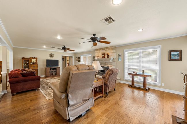 Living area with ornamental molding, ceiling fan, light wood-style floors, a fireplace, and recessed lighting | Image 4