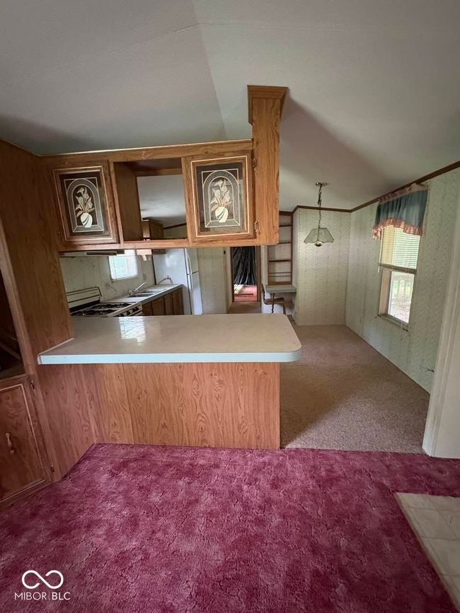 kitchen featuring carpet flooring, a peninsula, light countertops, and healthy amount of natural light | Image 13