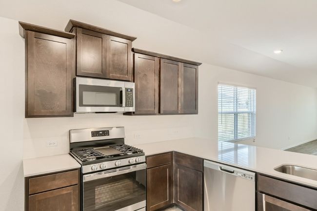 Kitchen with appliances with stainless steel finishes, light countertops, and dark brown cabinetry | Image 9
