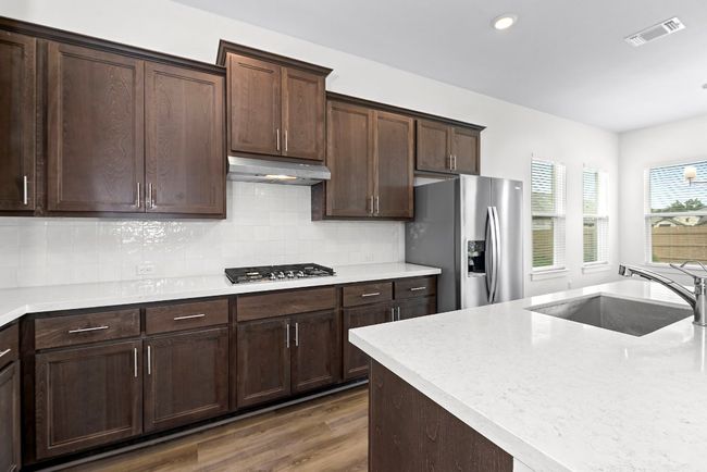 Kitchen with stainless steel appliances, a sink, under cabinet range hood, dark wood-style flooring, and tasteful backsplash | Image 16