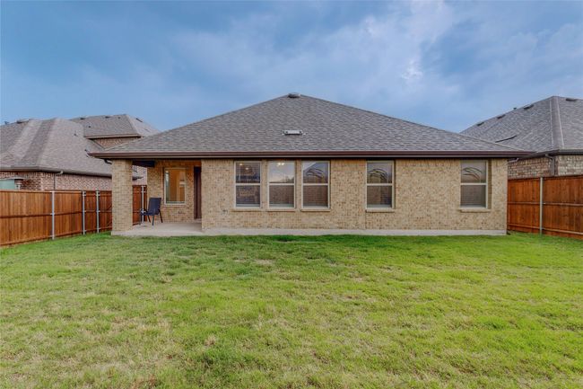 Back of house featuring a fenced backyard, a yard, brick siding, a shingled roof, and a patio area | Image 40