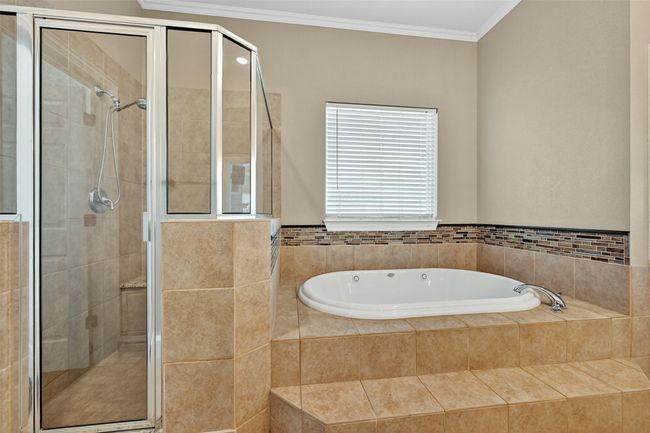 Bathroom featuring a bath, a shower stall, and crown molding | Image 25