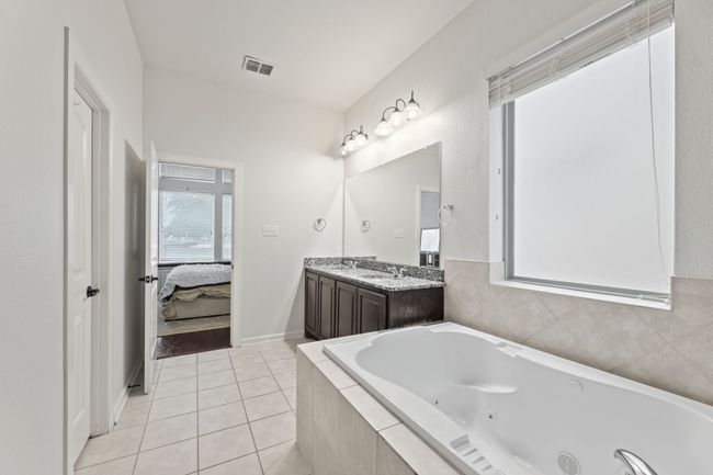 Ensuite bathroom featuring a tub with jets, double vanity, and tile patterned flooring | Image 20