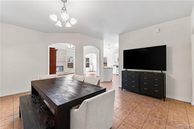 Dining space with arched walkways, a chandelier, light tile patterned floors, and a fireplace | Image 25