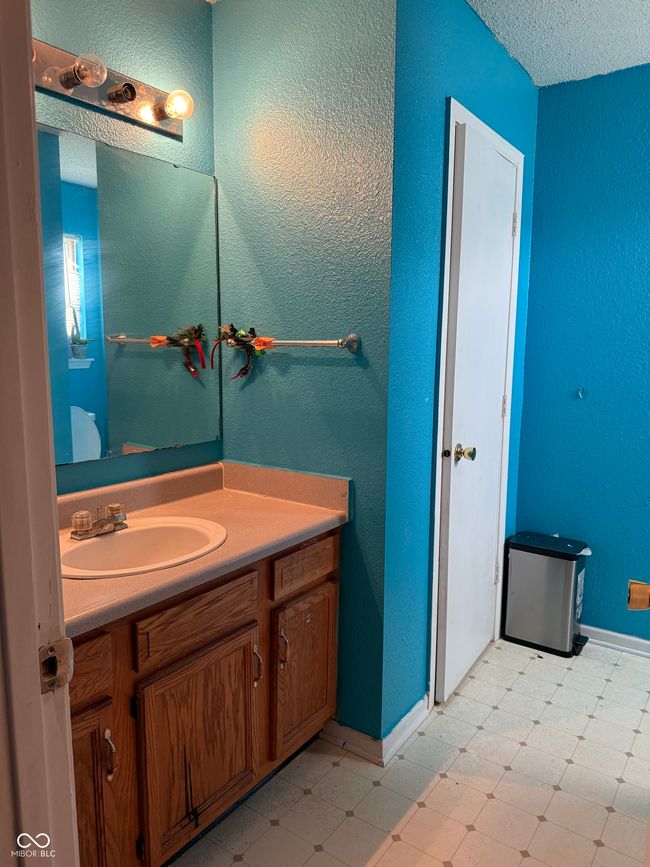 bathroom featuring tile patterned floors, vanity, and a textured wall | Image 8