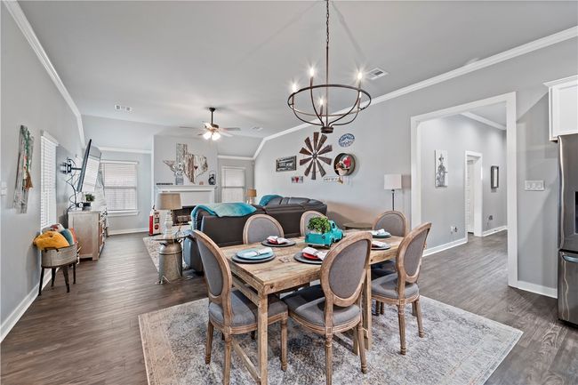 Dining space featuring visible vents, baseboards, ornamental molding, dark wood-type flooring, and ceiling fan with notable chandelier | Image 16