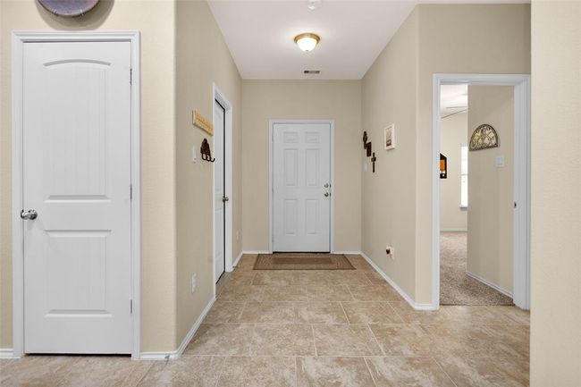 This view is looking back to the front door with garage access to the left and secondary bedroom on the right. | Image 10