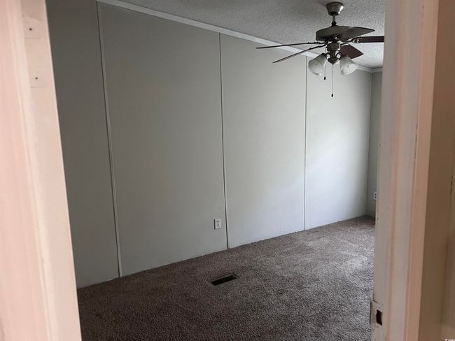 Carpeted spare room featuring a textured ceiling and ceiling fan | Image 8