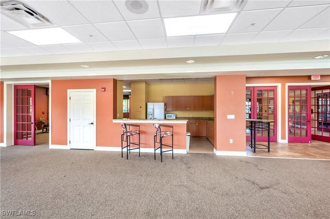 Community Kitchen featuring kitchen peninsula, a paneled ceiling, a kitchen bar, light colored carpet, and white refrigerator with ice dispenser | Image 25