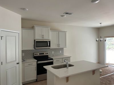 Kitchen with white cabinets, a center island with sink, stainless steel appliances, and sink | Image 3