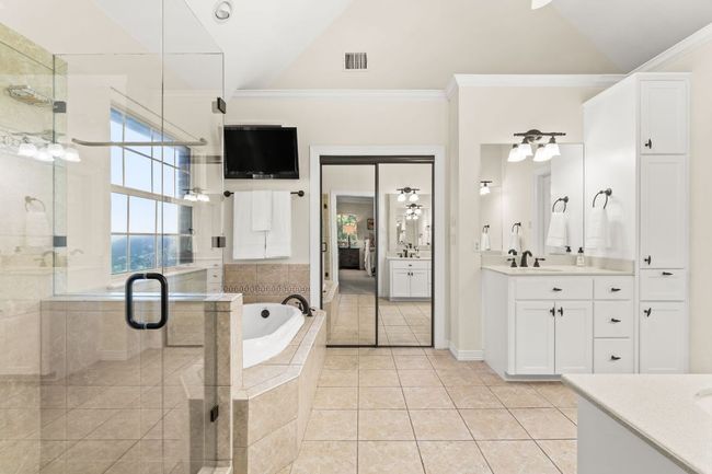 Primary Bath with a frameless shower door, a garden tub, double vanity and mounted television. | Image 17