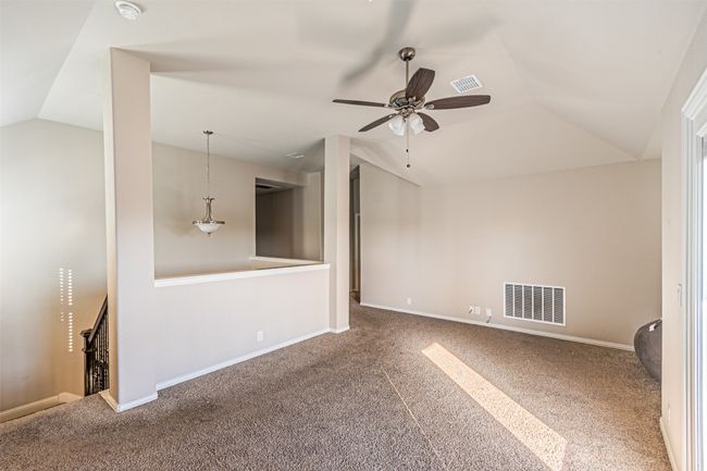 Carpeted empty room featuring lofted ceiling, ceiling fan, baseboards, and a smoke detector | Image 25