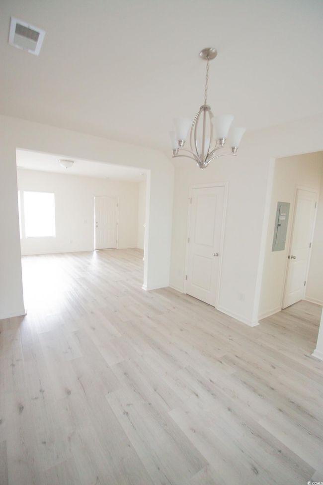Unfurnished dining area with a chandelier, light wood-style floors, electric panel, and baseboards | Image 6