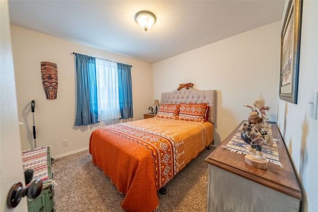 Bedroom featuring a textured ceiling, baseboards, and carpet floors | Image 13