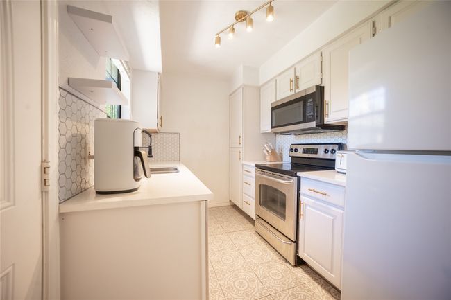 Kitchen featuring stainless steel appliances, backsplash, light countertops, a sink, and light tile patterned flooring | Image 13