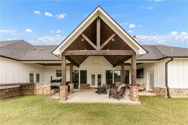 Rear view of property featuring french doors, board and batten siding, a yard, and a chimney | Image 25