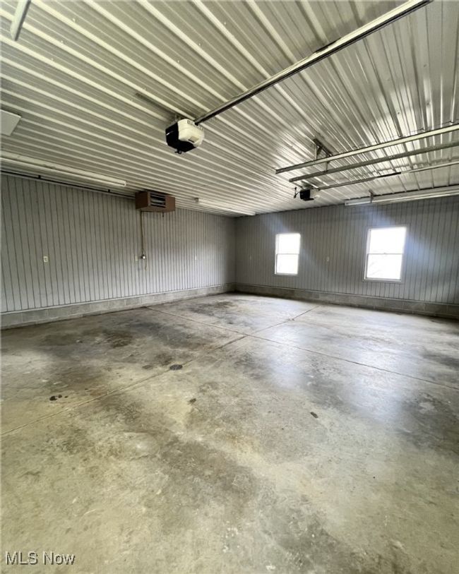 Garage featuring a wall mounted air conditioner, a garage door opener, and metal wall | Image 23