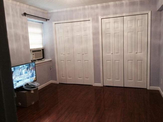 Unfurnished bedroom with two closets, dark wood-type flooring, cooling unit, and crown molding | Image 12