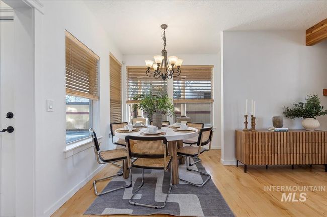 Dining area with healthy amount of natural light, wood finished floors, and a chandelier | Image 24