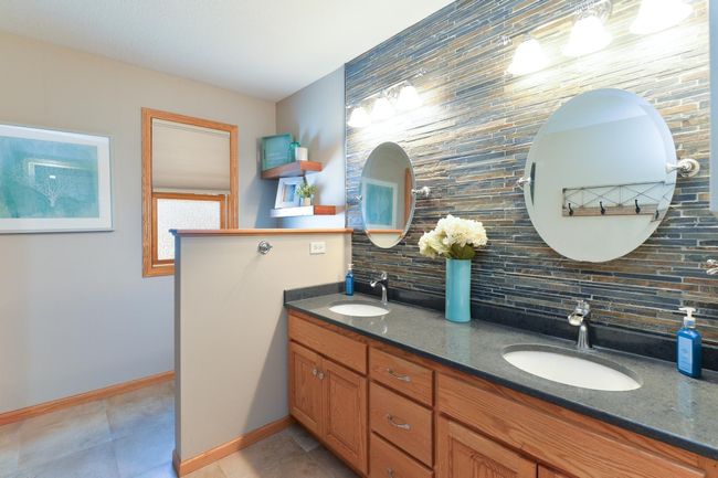 Primary bath is a retreat with quartz vanity top, dual sinks, and a huge walk in shower and tile surround | Image 16
